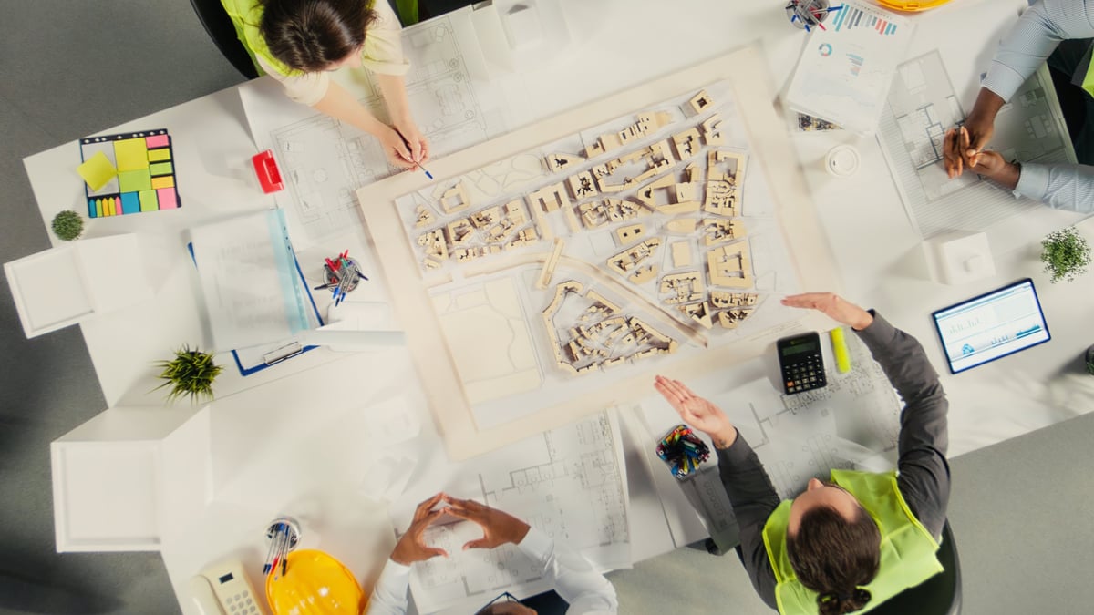 Top down view of architects and engineers collaborating on housing and city planning. teamwork, innovation and design as real estate experts plan residential project development.